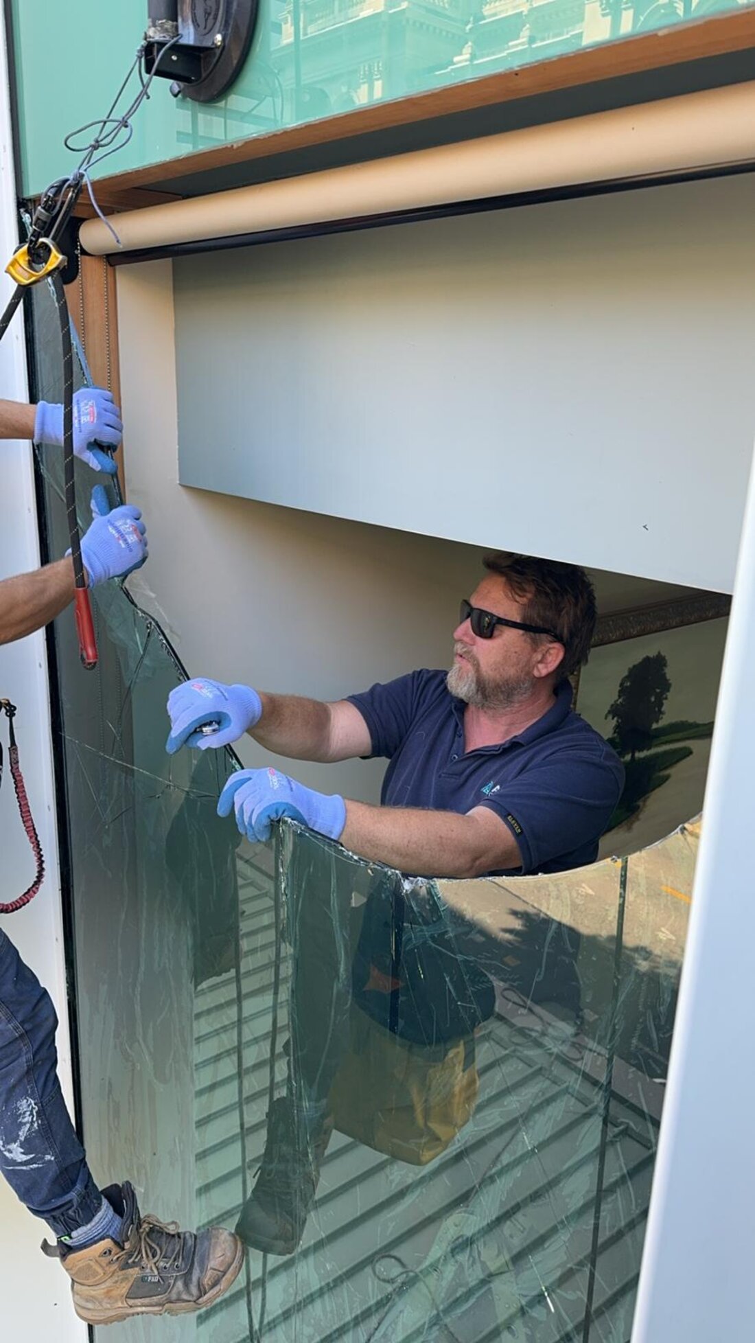 Peak Property Care technician removing a cracked glass panel during a glazing repair